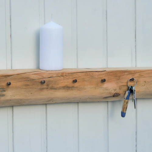 Handgeschmiedete Nägel in einem Fachwerkbalken mit natürlicher Holzmaserung zu einer Garderobe mit Ablage umfunktioniert. Nachhaltig & handgefertigt.