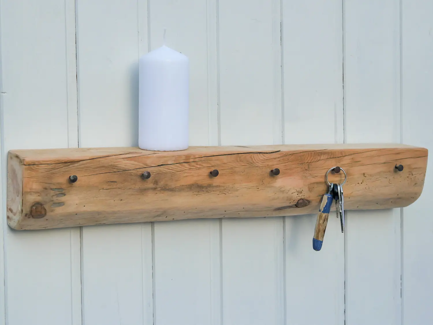 Handgeschmiedete Nägel in einem Fachwerkbalken mit natürlicher Holzmaserung zu einer Garderobe mit Ablage umfunktioniert. Nachhaltig & handgefertigt.