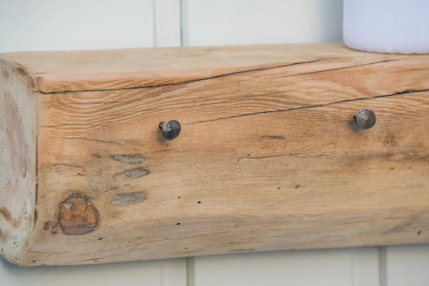 Handgeschmiedete Nägel in einem Fachwerkbalken mit natürlicher Holzmaserung zu einer Garderobe mit Ablage umfunktioniert. Nachhaltig & handgefertigt.