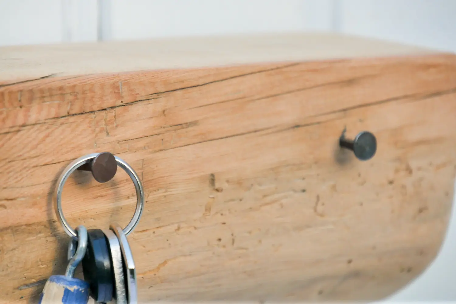 Handgeschmiedete Nägel in einem Fachwerkbalken mit natürlicher Holzmaserung zu einer Garderobe mit Ablage umfunktioniert. Nachhaltig & handgefertigt.
