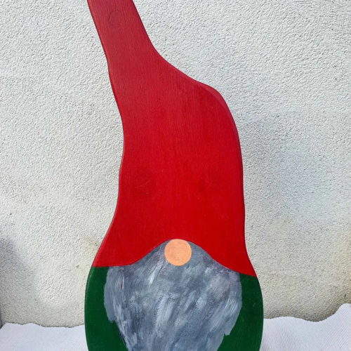 Detailaufnahme eines rustikalen Holzwichtels mit Zipfelmütze, handgefertigte Dekoration im nordischen Stil vor natürlichem Hintergrund. Nachhaltig & handgefertigt.