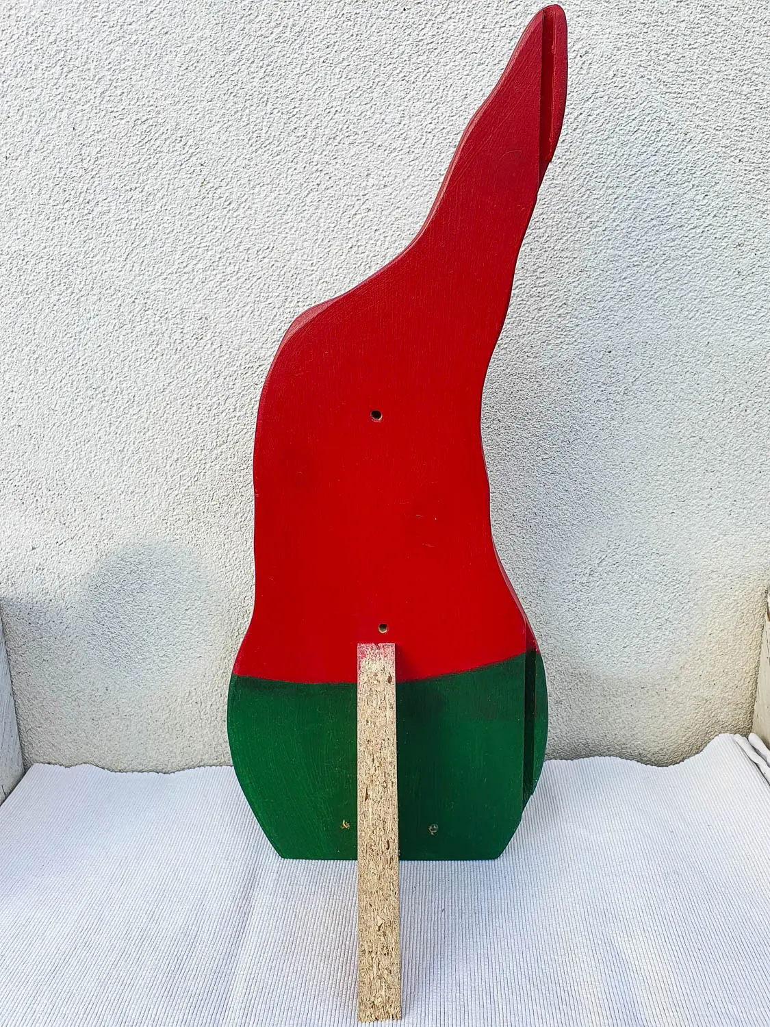 Detailaufnahme eines rustikalen Holzwichtels mit Zipfelmütze, handgefertigte Dekoration im nordischen Stil vor natürlichem Hintergrund. Nachhaltig & handgefertigt.
